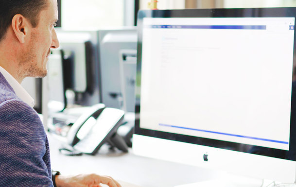 Een man die aan een bureau zit en een computer gebruikt